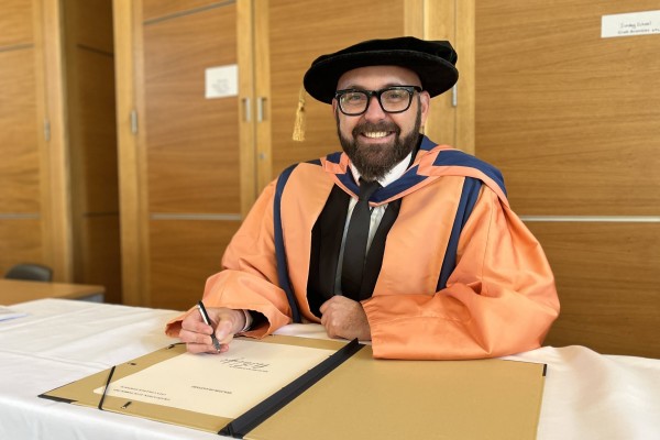 Richard Bainbridge signing the conferment of his honorary doctorate in the Bowerbank room at Norwich Cathedral.