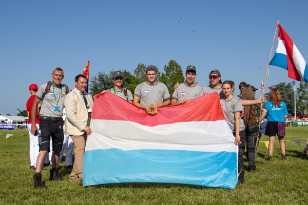 Group picture of the winning students and team coaches from Luxembourg with the national flag